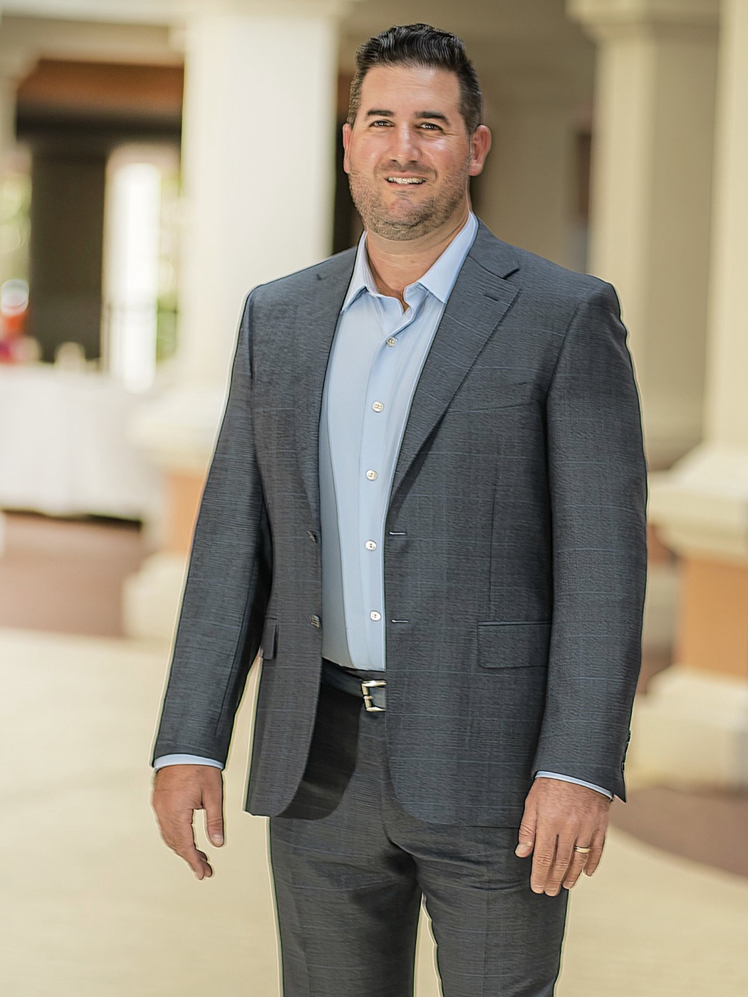 Anthony Lombardo in a grey suit beneath the arches of a coastal resort